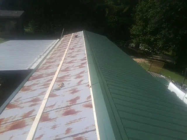 Old rusted panels beside newly installed green metal roofing — Wind Damage Roof Repair by Roofing Brothers in Pine Valley