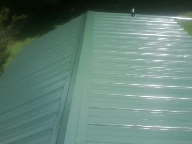 New green metal panels meeting at the ridge of a roof — Flat Roof Repair work by our crew in Pine Valley
